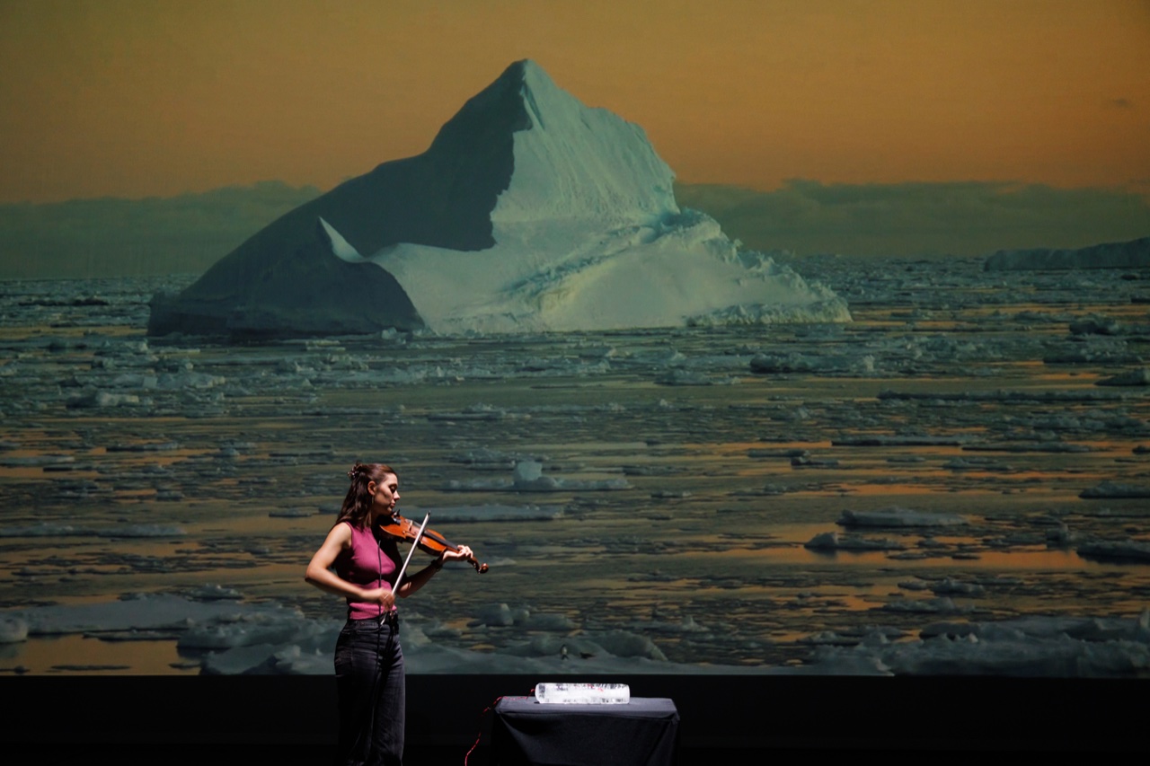 Sastrugi performance at Rawspace, with a violinist before Antarctic sea-ice imagery.